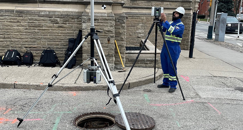 Operator using the Leica RTC360 3D laser scanner at an open manhole at the univesity of Toronto