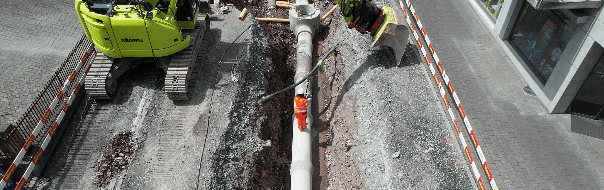 Pipe surveying with Leica AP20 AutoPole and TS16 robotic total station from Leica Geosystems on construction site with excavator.