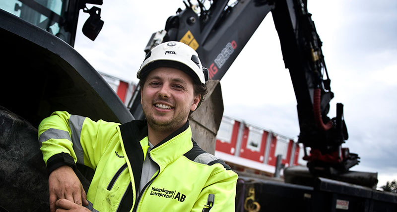 Jonas Kilsgard in front of the Huddig backhoe with machine control from Leica Geosystems